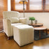 White upholstered armchair with matching ottoman. Relaxing living room furniture set with a modern lamp on a coffee table